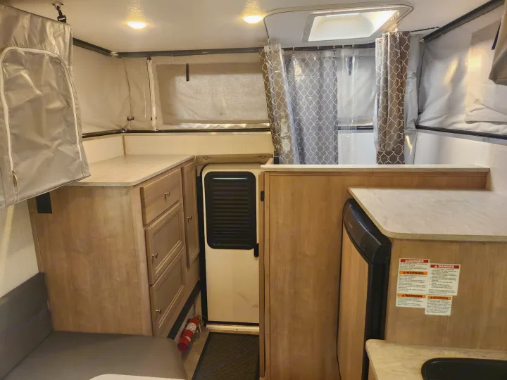 Compact interior of an rv rental features a kitchen, shower, and convertible sleeping areas.. Palomino SS1500 2023