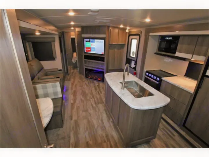 Modern RV rental interior: kitchen island, living area w/ recliners & fireplace, TV.. Grand Design Imagine 2023