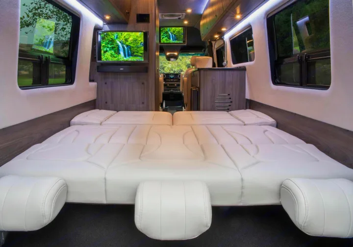 Luxury RV rental interior with a spacious, comfortable bed, dual TVs, and elegant wood paneling, perfect for your next adventure.. Grech RV Strada-ion 2024