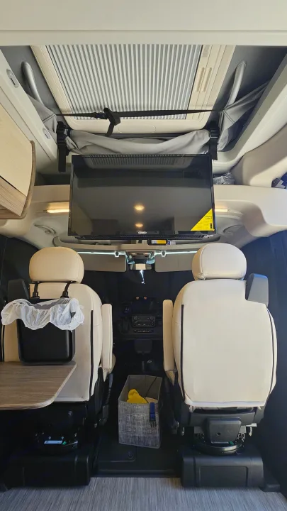 **rv rental** interior: comfortable swivel seats, mounted TV, fold-out table, and overhead amenities.. Entegra Coach Ethos 2024