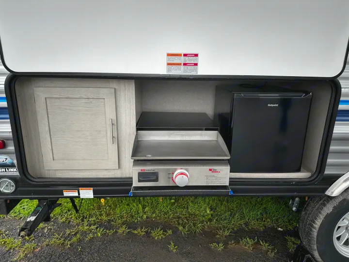 This RV rental features a convenient outdoor kitchen with a griddle, compact refrigerator, and storage cabinet.. Coachmen Catalina 2022