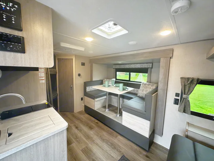 Explore this modern RV rental: comfortable dinette, kitchen, & bunk beds with stylish wood-look floors.. Coachmen Catalina 2022