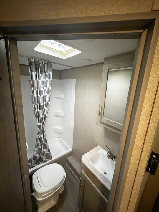 Compact RV rental bathroom with toilet, vanity sink, shower, and ceiling vent.. Coachmen Catalina 2022