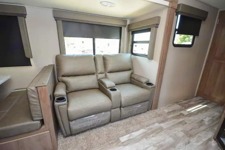 Comfortable RV rental living space featuring theater seating recliners, dinette, & windows.. Grand Design Imagine 2023