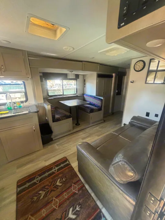 Inside this RV rental: modern kitchen, cozy dinette, and plush living area with a dark couch. Perfect for travel.. Prime Time Tracer 2021