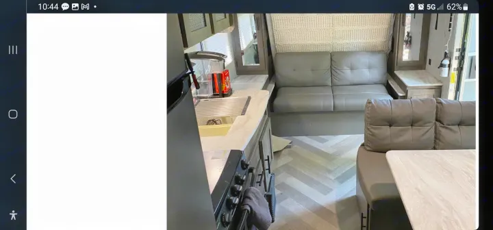RV rental interior featuring a compact kitchen with sink, stove, and a cozy living area with seating, table, and herringbone flooring.. Forest River Salem 2020
