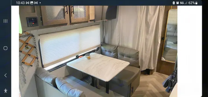 Cozy RV rental interior: dining booth, table, window with blinds, overhead cabinets, TV, and a coat rack for convenience.. Forest River Salem 2020