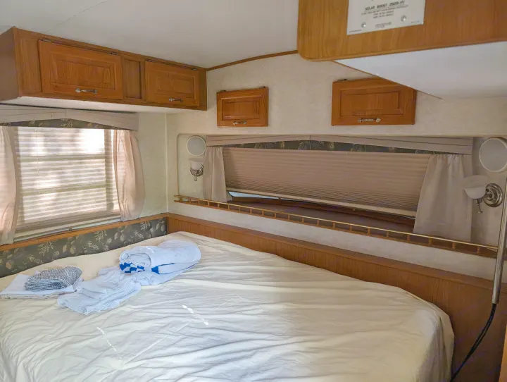 Cozy RV rental bedroom featuring a bed, wood cabinets, and large windows with blinds.. Hi Lo 2307c 2007
