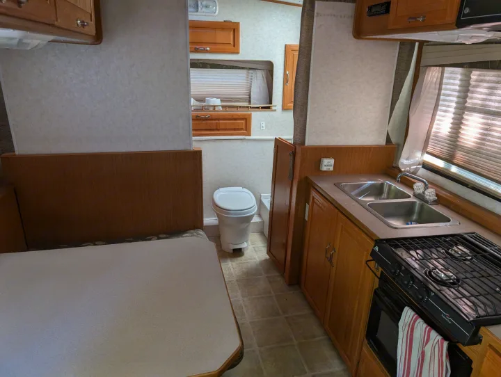 RV rental interior: kitchen with dual sinks, stove/oven; adjacent toilet and dining booth.. Hi Lo 2307c 2007