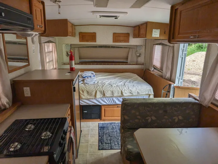 An RV rental interior, showcasing a kitchen, a made bed, and a dinette. Equipped for comfortable travel.. Hi Lo 2307c 2007