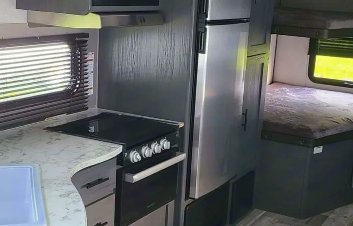 Modern RV rental interior showcases a fully equipped kitchen with stove, oven, fridge, microwave, plus cozy bunk beds.. Aspen Trail LE 2021