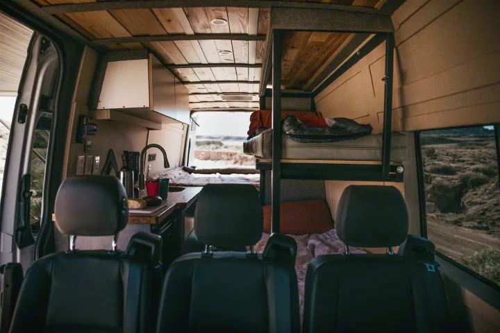 View inside a spacious rv rental van with a full kitchenette, wooden ceiling, and comfortable bunk beds for mobile living.. Mercedes Mercedes Benz Sprinter Custom Van Conversion 2020