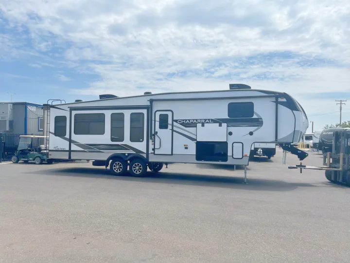 This white Coachmen Chaparral fifth-wheel RV, ideal for an rv rental, is parked outdoors, showcasing its spacious exterior.. Coachmen Chapparal 336 TSIK 2022