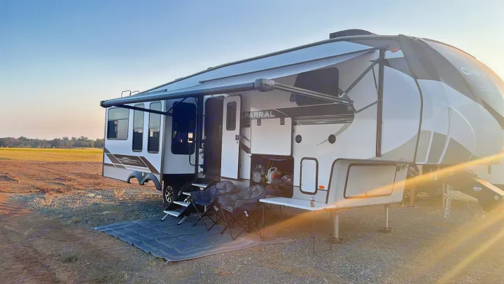 This spacious fifth-wheel RV rental is perfectly set up for an outdoor camping trip, with an extended awning, chairs, and table.. Coachmen Chapparal 336 TSIK 2022