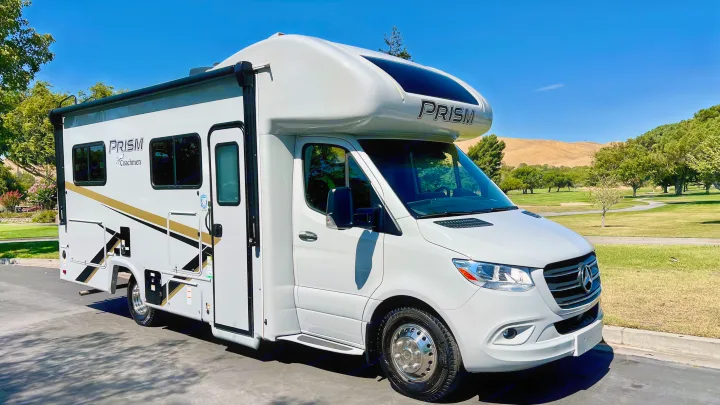 RV rental: Sleek white Coachmen Prism Class C motorhome on Mercedes-Benz chassis in a sunny park setting.. Coachmen Prism 2024