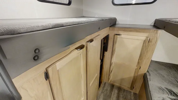 Inside an RV rental: Grey bunk beds are stacked above wooden storage cabinets, offering compact sleeping and organization.. Forest River Cherokee Grey Wolf 2022