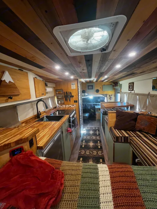 Cozy, custom RV rental interior with wood details, kitchen, dining, and sleeping areas. Perfect camper experience.. Chevrolet Express 2011