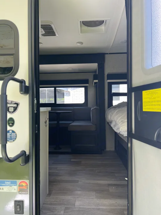 Interior of an RV rental, showing a dinette, bed, and overhead AC unit. Ideal for compact travel.. Jayco Jay Feather Micro 2022