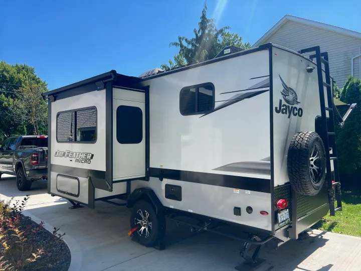 Sleek Jayco Feather Micro travel trailer, ideal for an rv rental, parked on a sunny driveway with a truck in the background.. Jayco Jay Feather Micro 2022