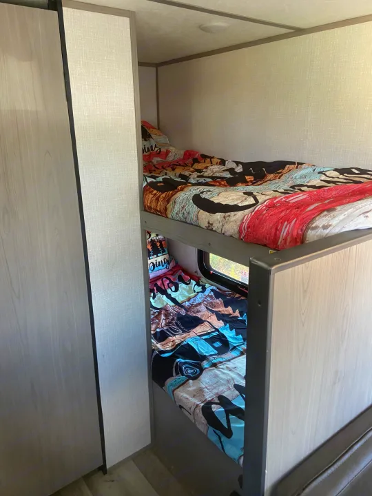 RV rental bunk beds provide a cozy, compact sleeping area with a window, perfect for family adventures.. Dutchmen Coleman Lantern LT 2023