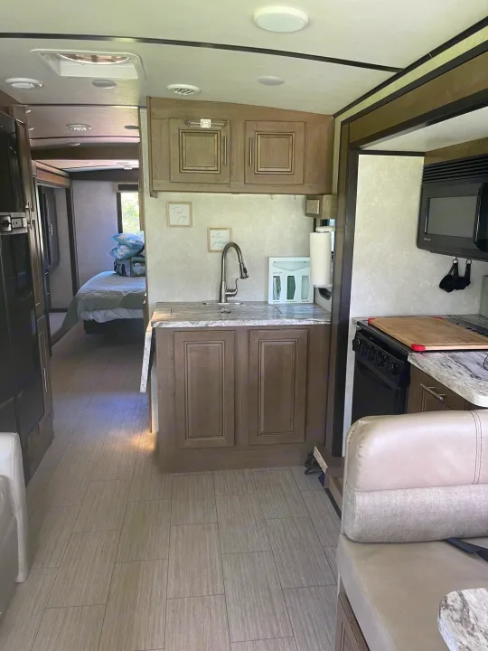 RV rental interior: a compact kitchen with a sink, microwave, and stove, leading to a bedroom in the background.. FR3 FR3 Motorhome 2020