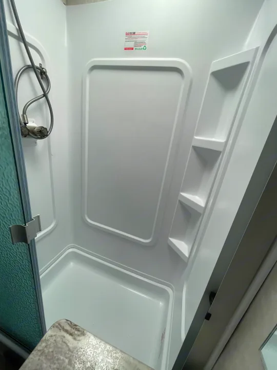 This clean white shower in an RV rental features a flexible showerhead, easy controls, and practical built-in shelves.. FR3 FR3 Motorhome 2020