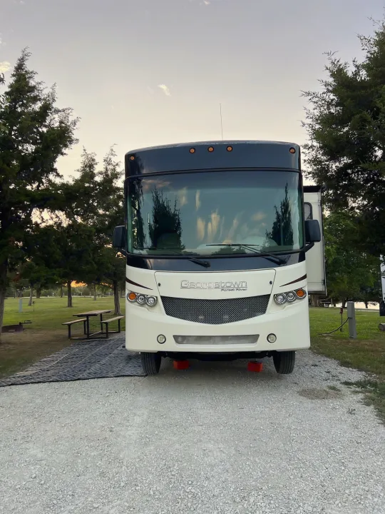 A large white and black Georgetown RV, ideal for an rv rental, parked on gravel at a shaded campsite with a picnic table.. Georgetown Georgetown Motorhome 2016
