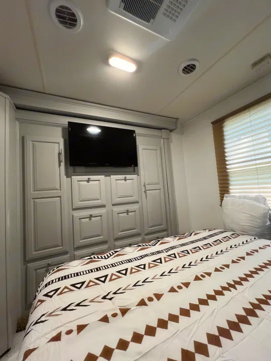 Cozy RV rental bedroom with built-in storage, TV, and patterned bedding. Perfect for comfortable travel.. Georgetown Georgetown Motorhome 2016