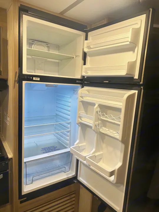 Empty, clean two-door RV rental fridge/freezer showing leveling instructions for propane/electric.. Coachmen fet257bhs-320 2021