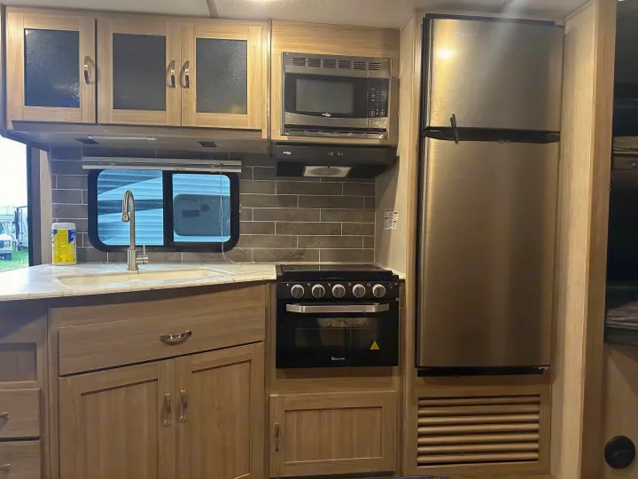 This well-appointed rv rental kitchen includes a microwave, stove, oven, fridge, sink, and ample storage cabinets for travel.. Coachmen fet257bhs-320 2021