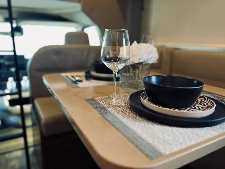 A set dining table with elegant black and white dishware and a wine glass inside a modern rv rental interior.. Winnebago Minnie Winnie 2022
