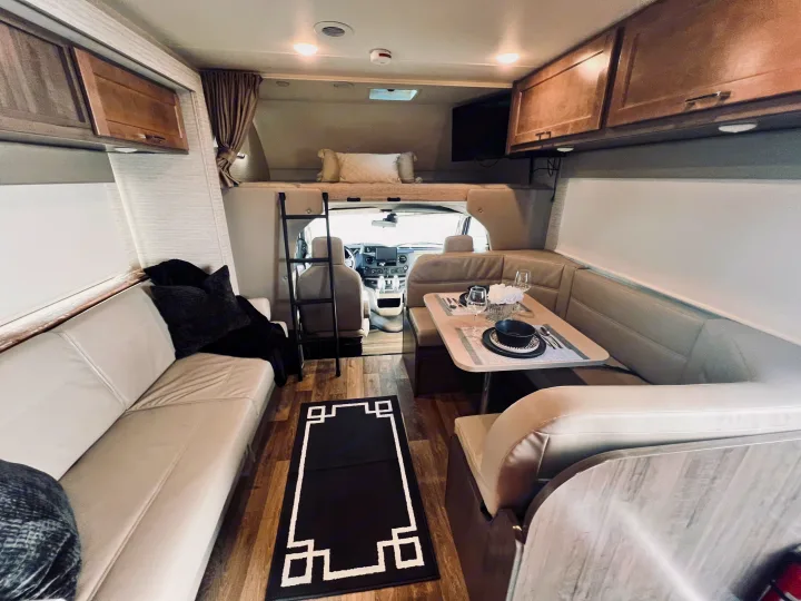 Spacious RV rental interior featuring a comfy sofa, dining area, and bunk bed. Ready for your next adventure!. Winnebago Minnie Winnie 2022