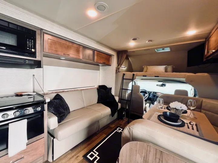 Tour this clean rv rental interior featuring a bright kitchen, cozy dining booth, sofa, and comfortable bed.. Winnebago Minnie Winnie 2022