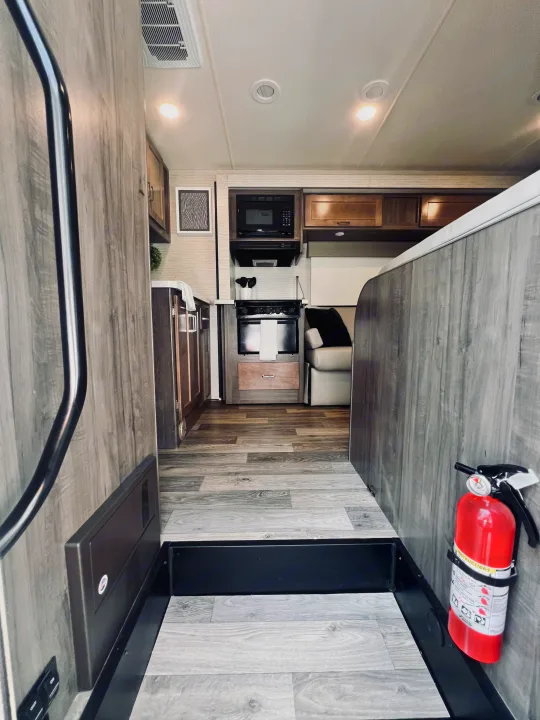RV rental interior showcasing a compact kitchen, comfortable living area, and essential fire safety equipment.. Winnebago Minnie Winnie 2022