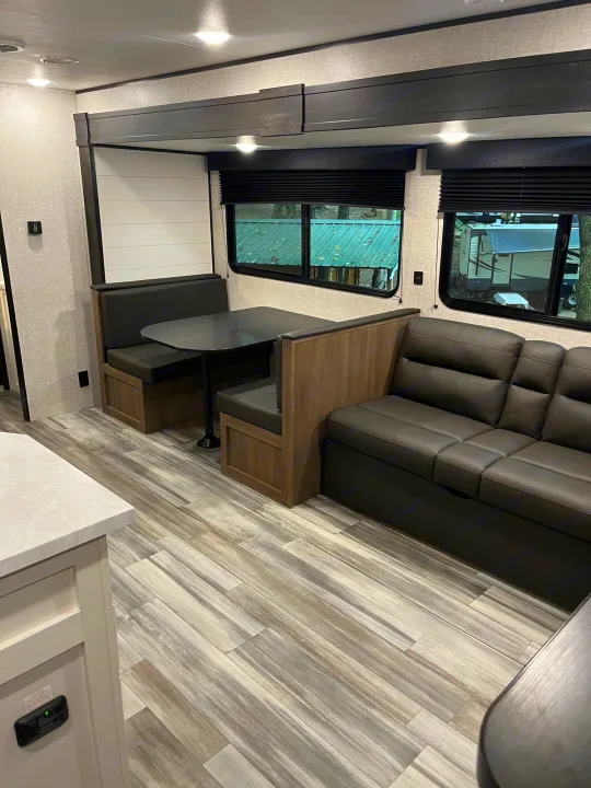 Spacious RV rental interior featuring a cozy dinette, comfortable sofa, and modern wood flooring, ready for your adventure.. Jayco JayFlight SLX 2024