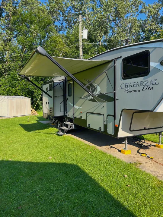 Spacious Chaparral RV rental set up with awning extended, parked on a concrete pad amidst green grass.. Forest River Coachmen Chaparral Lite 2019