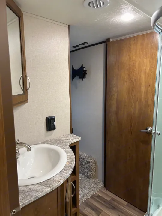 This RV rental's bathroom features a vanity with a sink, mirror, and an adjacent shower, offering comfort on the go.. Forest River Coachmen Chaparral Lite 2019