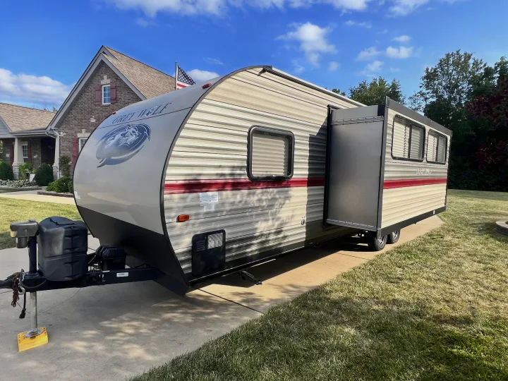 Grey Wolf travel trailer, a spacious rv rental, parked in a driveway with its slide-out extended. Sunny residential setting.. Forest River Cherokee Grey Wolf 2019