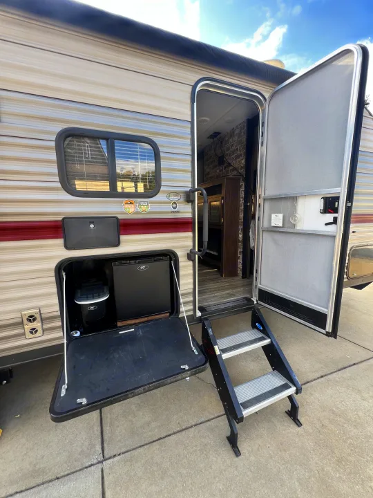 This rv rental showcases an open entry with steps, an outdoor kitchen with mini-fridge & ice maker, and a rolled-up awning.. Forest River Cherokee Grey Wolf 2019