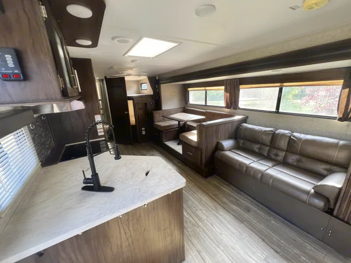 Spacious rv rental interior with a modern kitchen, dinette seating, comfy sofa, and wood-look floors. Ready for travel!. Forest River Cherokee Grey Wolf 2019