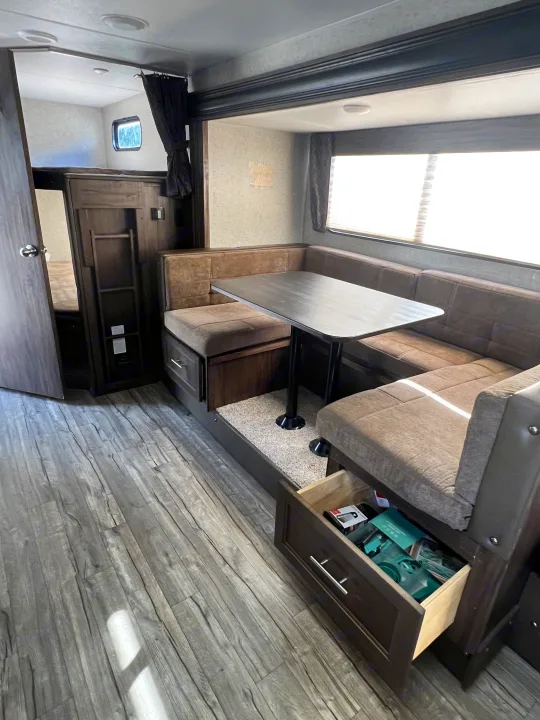 This RV rental's interior features a practical dinette with storage, nearby bunk beds, and modern laminate flooring.. Forest River Cherokee Grey Wolf 2019