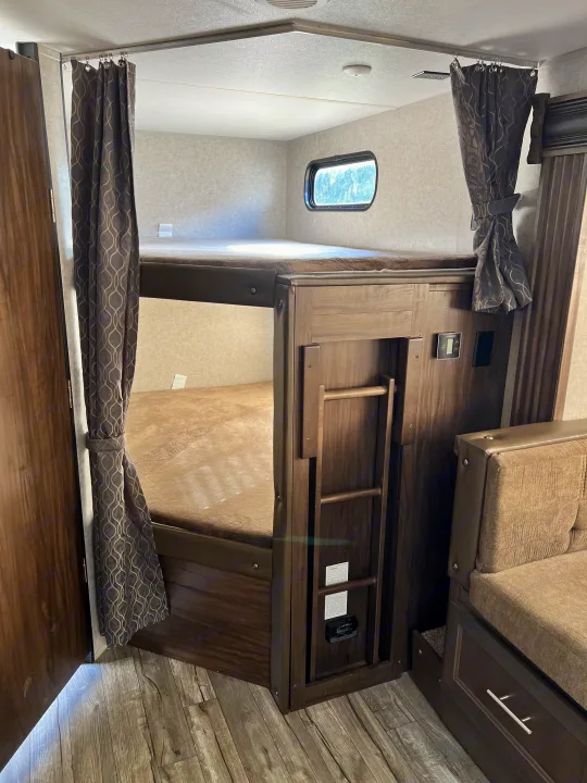 RV rental interior: cozy bunk beds with privacy curtains, ladder, window, and a control panel for comfortable stays.. Forest River Cherokee Grey Wolf 2019