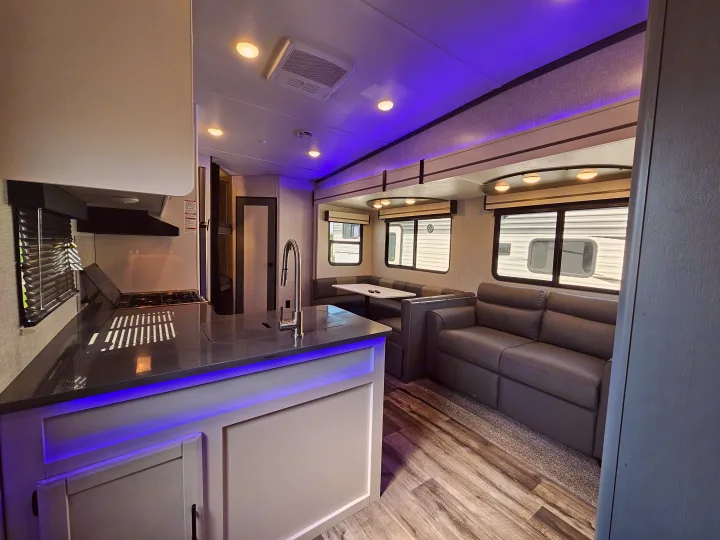 Bright RV rental interior: modern kitchen island, stove, sink, cozy dinette, & sofa. Perfect for travel!. Crossroads Volante 2023
