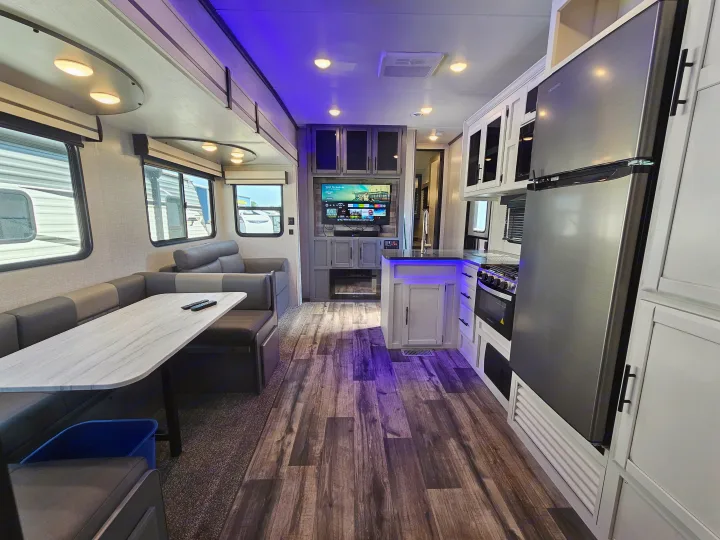 Spacious RV rental interior featuring a modern kitchen, dinette, and entertainment area with blue ambient lighting.. Crossroads Volante 2023