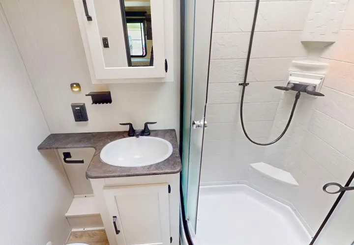 Modern RV rental bathroom featuring a shower, sink vanity, and mirror, designed for comfort on the go.. Forest River Puma 2023