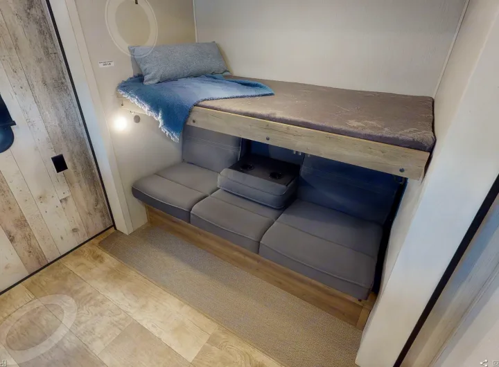 Cozy RV rental features a top bunk bed, a lower sofa with cup holders, and a light-wood interior.. Forest River Puma 2023