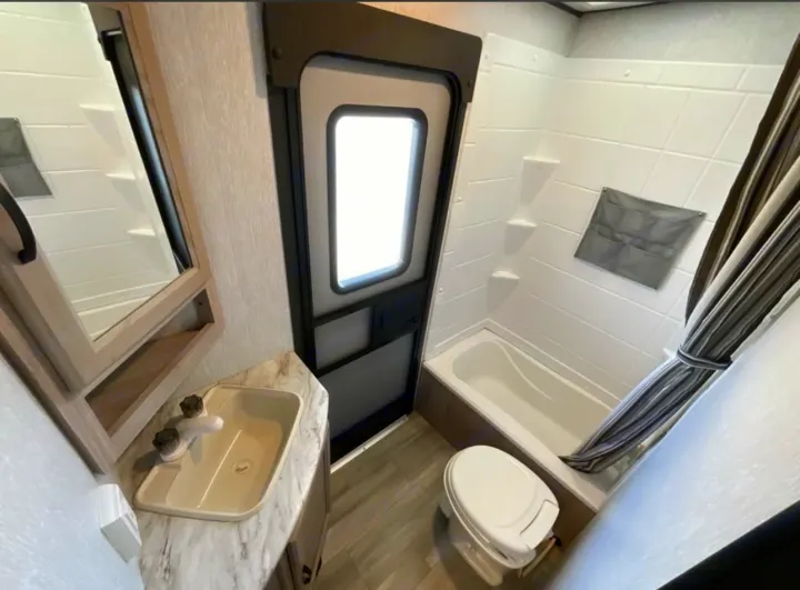 Compact RV rental bathroom features a sink with a mirror, a toilet, and a combined bathtub/shower.. Coachmen 2021 Coachman Sprinter Campfire Edition 2021