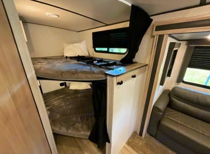 Modern RV rental interior with bunk beds, a ladder for the top bed, and a comfortable grey sofa.. Coachmen 2021 Coachman Sprinter Campfire Edition 2021