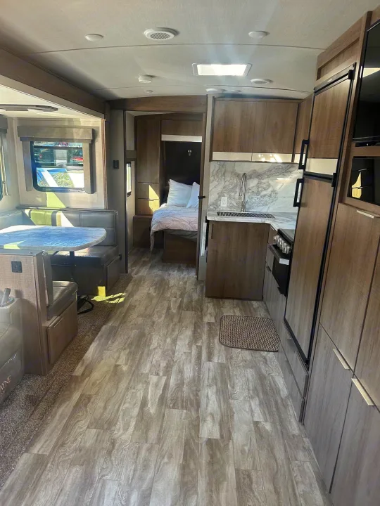 This RV rental interior features a modern kitchen, dinette, and cozy bedroom. Ideal for comfortable travel.. Grand Design Imagine 2020