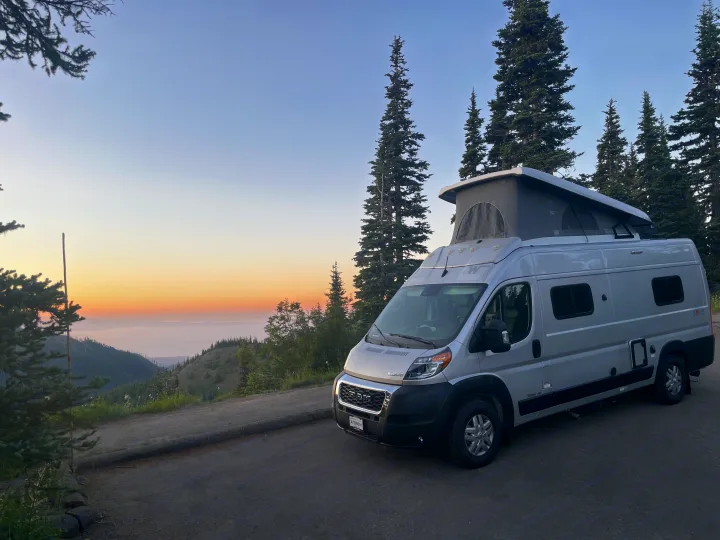 Silver camper van (RV rental) at sunset, pop-top open, on a mountain overlook with distant valley views.. Other Other 2022